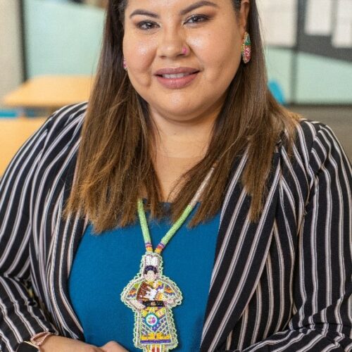 A woman in a striped blazer smiles in an office setting