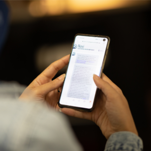 a person holds a smartphone, open to the UofT Navi mental health app.